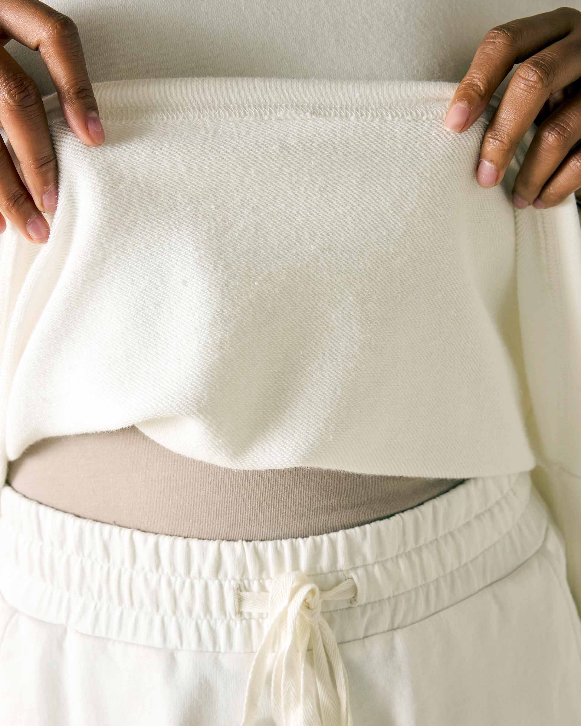 Person wearing a cream-colored outfit with a textured fabric pattern.
