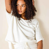 Woman wearing a white outfit against a beige background