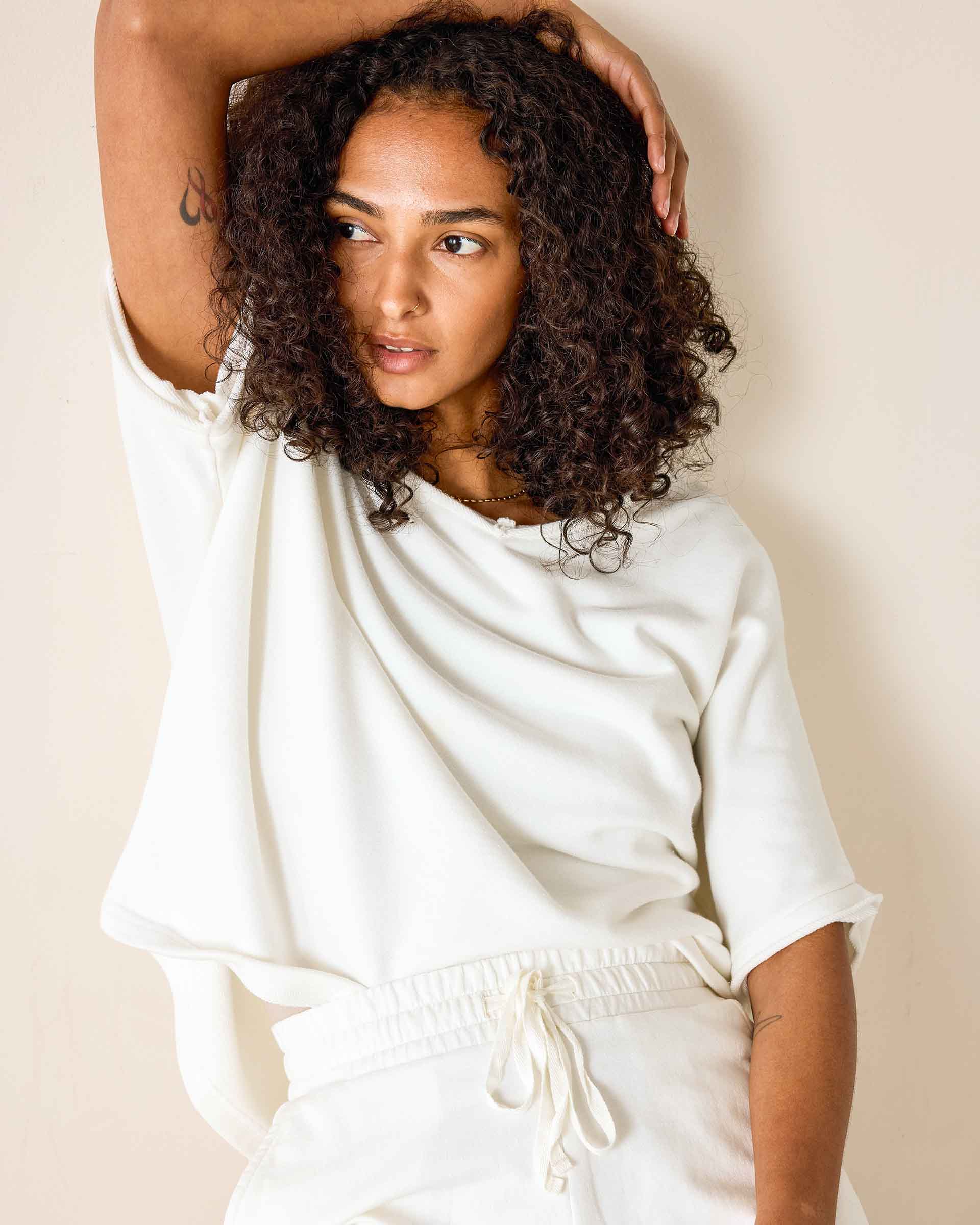 Woman wearing a white outfit against a beige background
