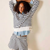 Woman wearing a striped outfit with shorts against a plain background