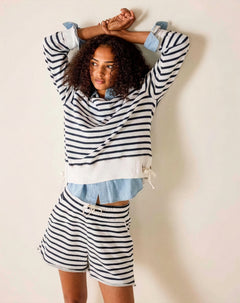 Woman wearing a striped outfit with shorts against a plain background