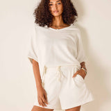 Woman wearing a white outfit against a plain background