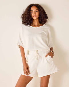 Woman wearing a white outfit against a plain background