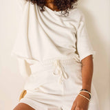 Person wearing a white outfit with a neutral background