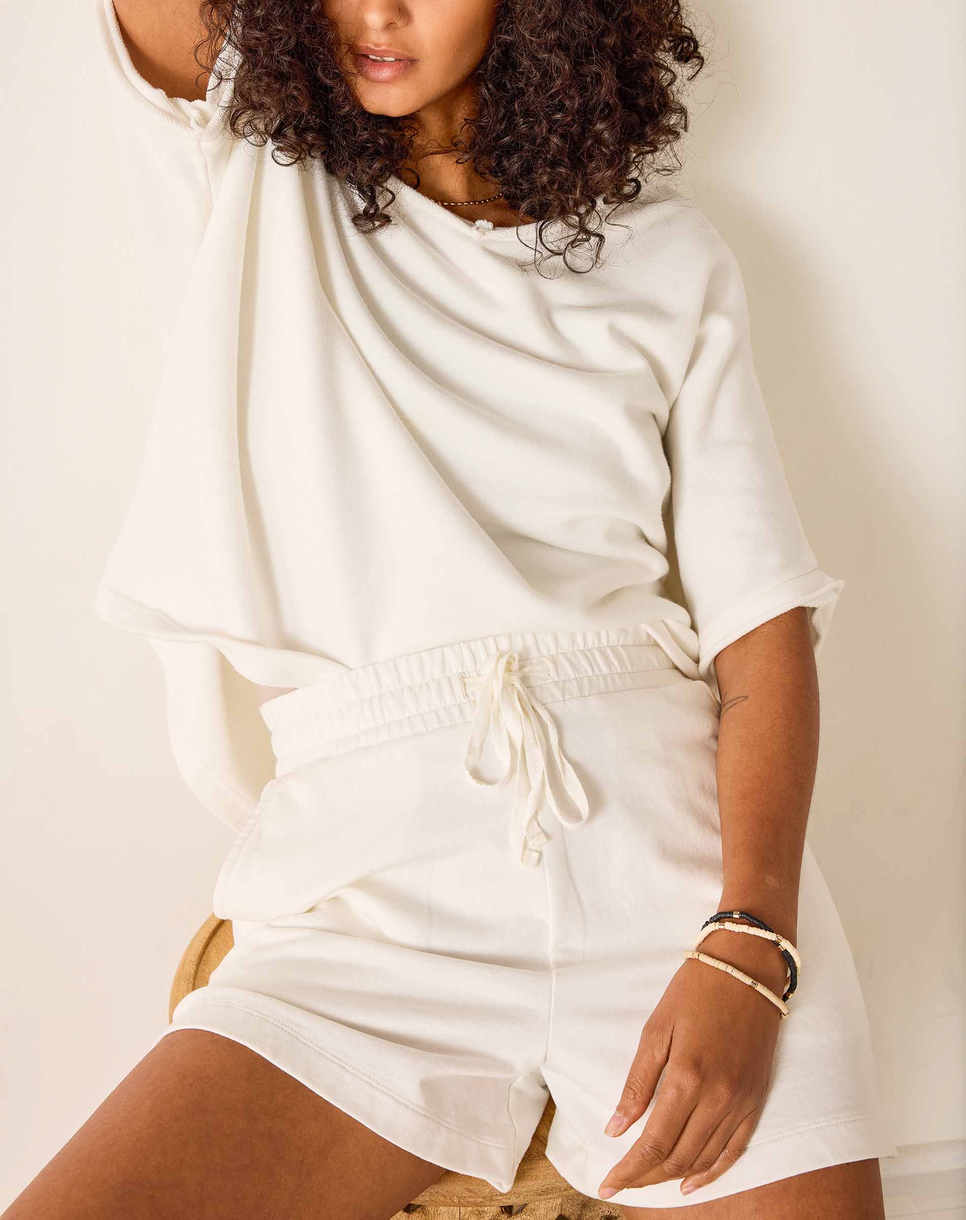 Person wearing a white outfit with a neutral background