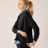 Side view of women's travel-friendly black knit top with a side zip and layered blue shirt.