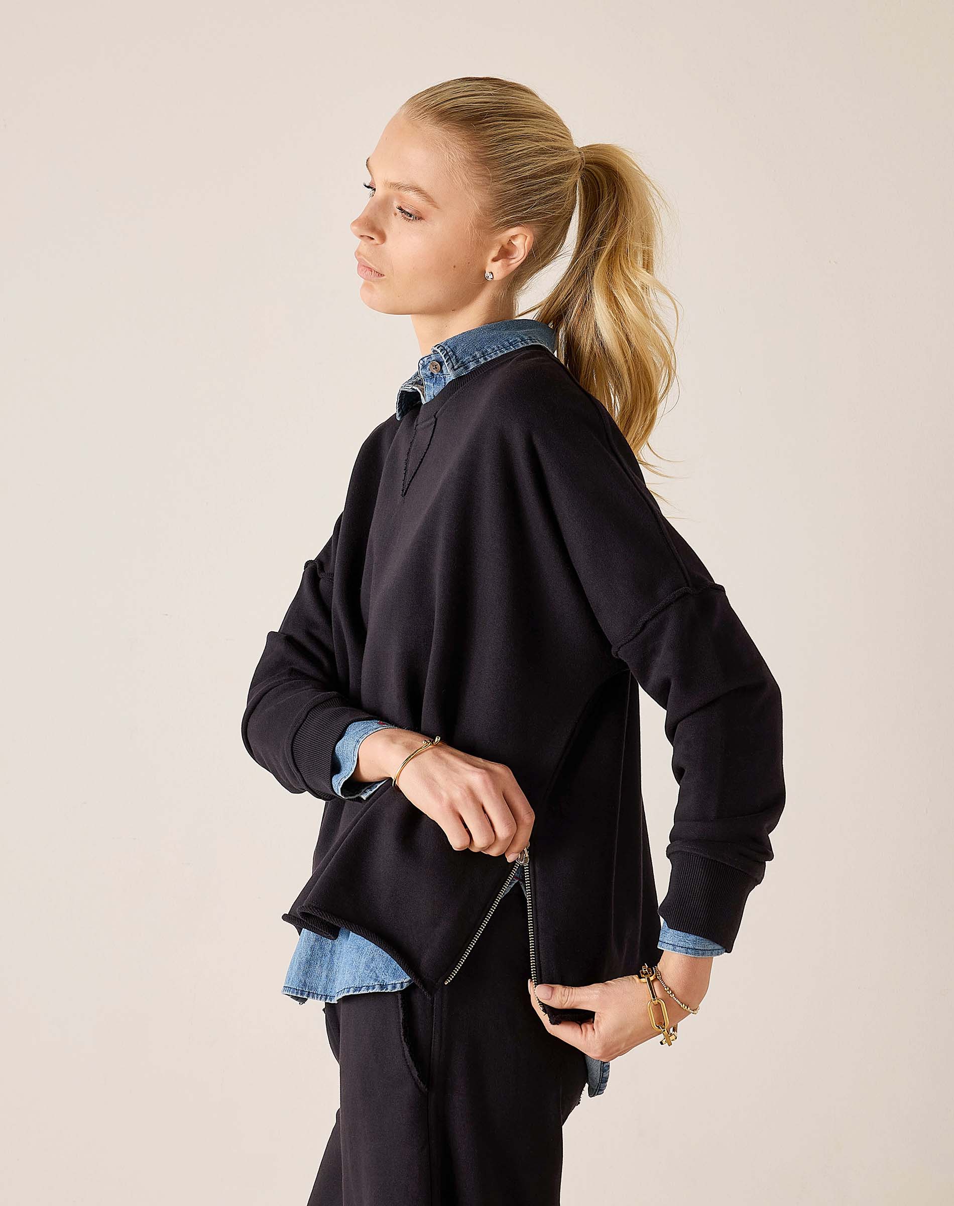 Side view of women's travel-friendly black knit top with a side zip and layered blue shirt.