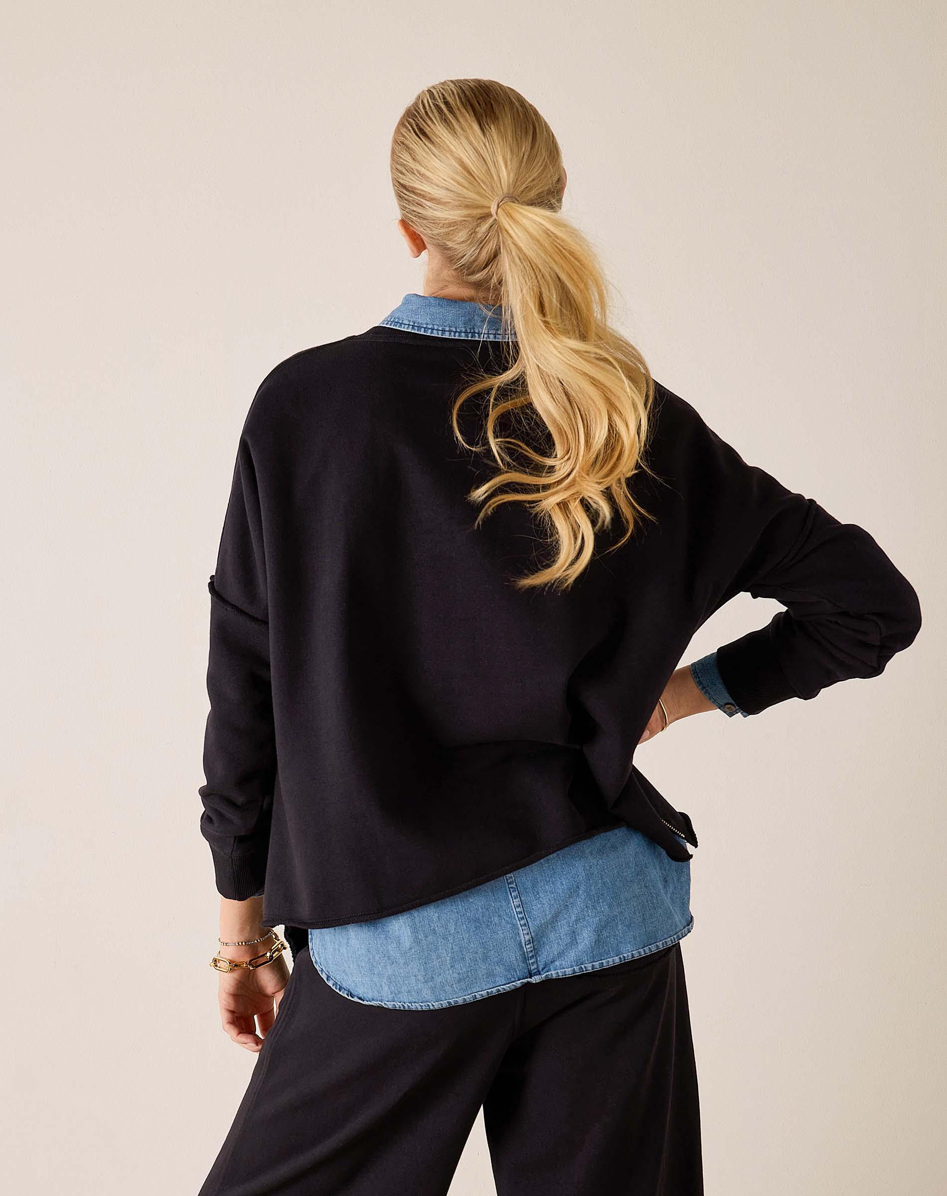 Back view of women's travel-friendly black Frenchie top with long sleeves and a layered denim shirt.
