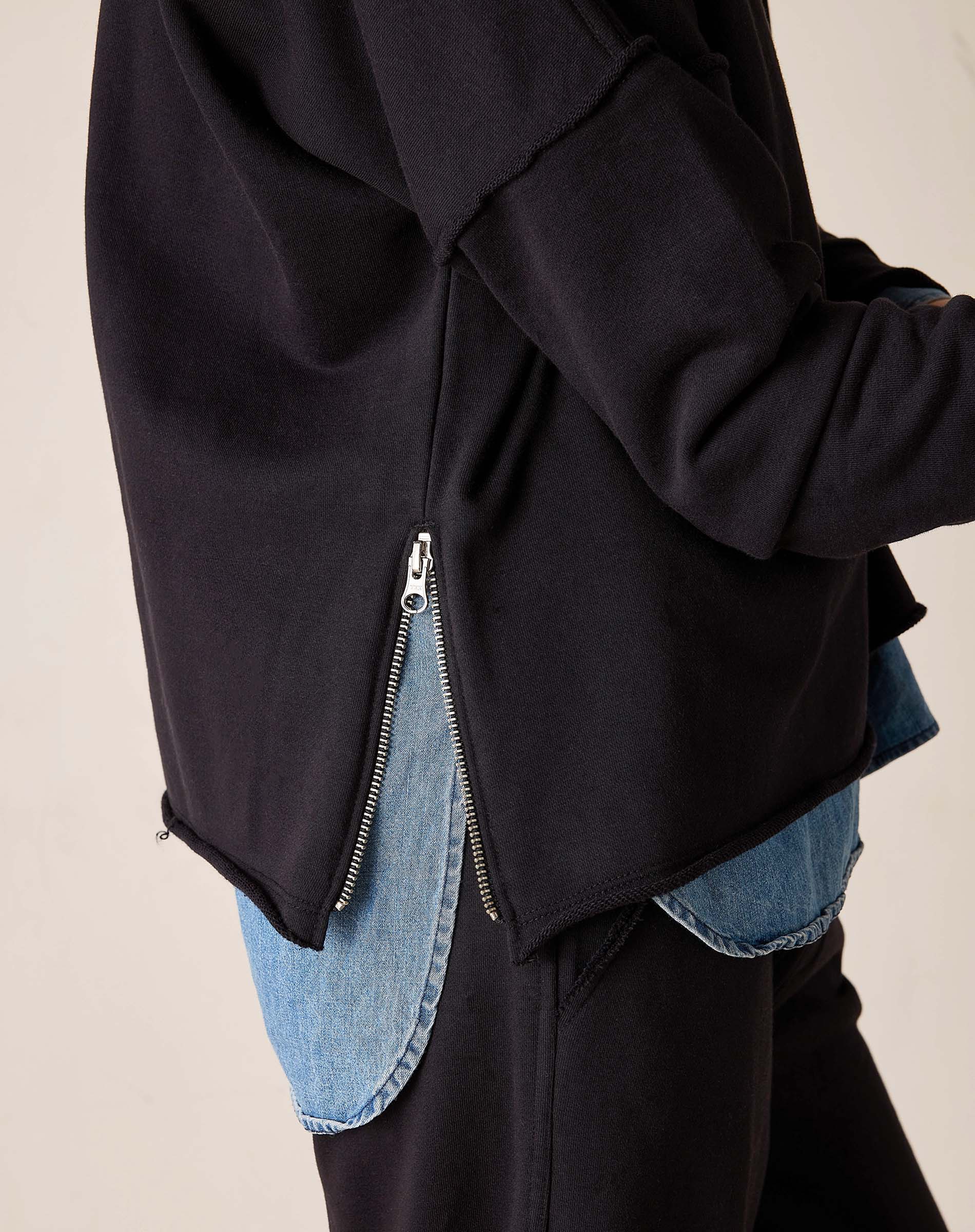 Side view of women's travel-friendly black knit top with a side zip detail.
