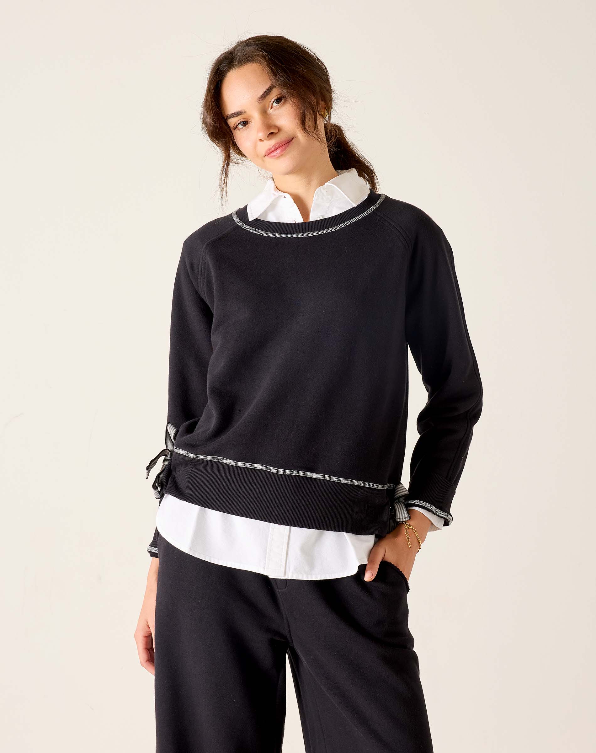 Woman wearing a black sweater with white trim on a beige background