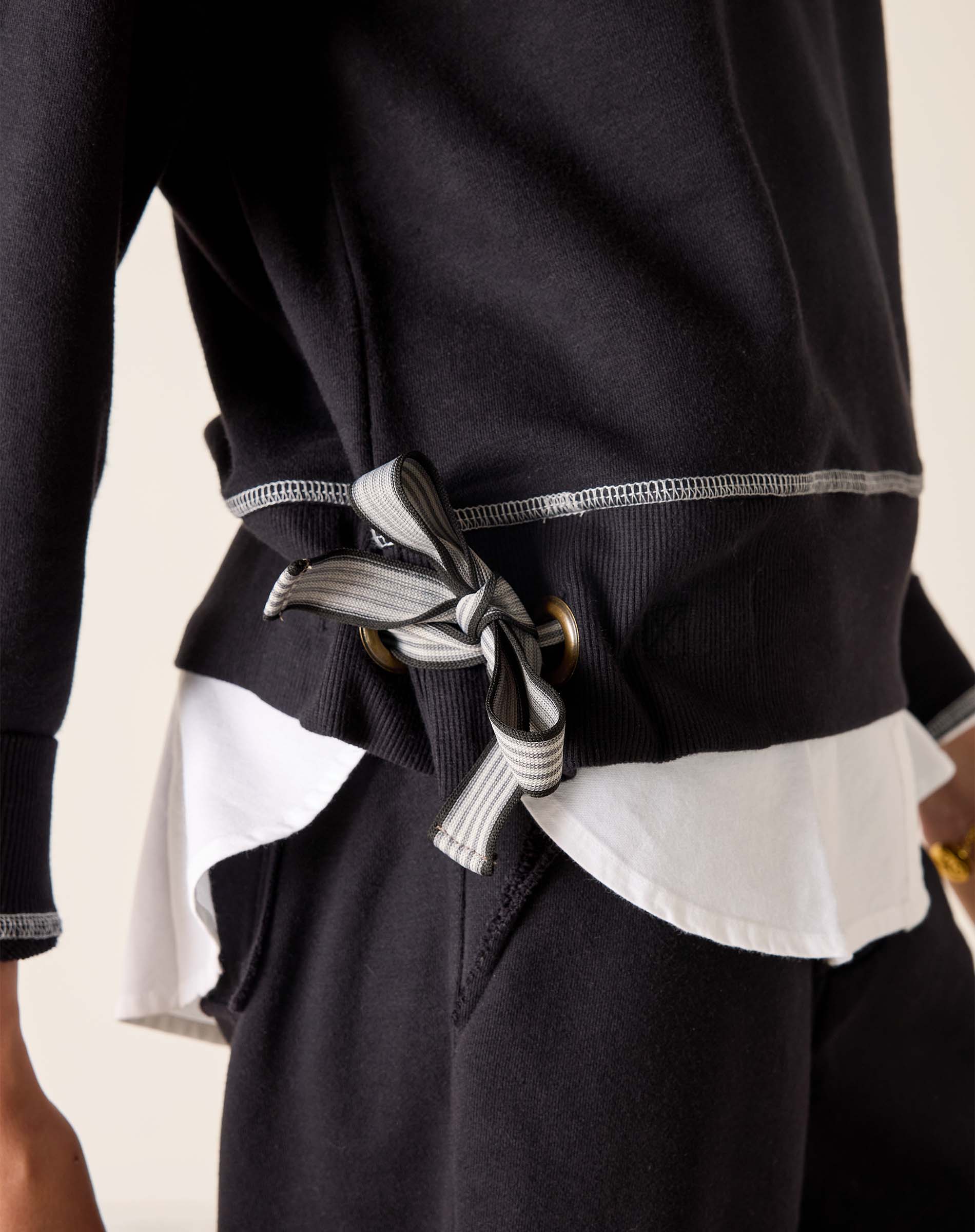 Black outfit with a white shirt and belt detail on a neutral background
