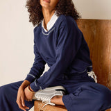 Person wearing a navy blue outfit sitting on a wooden chair.