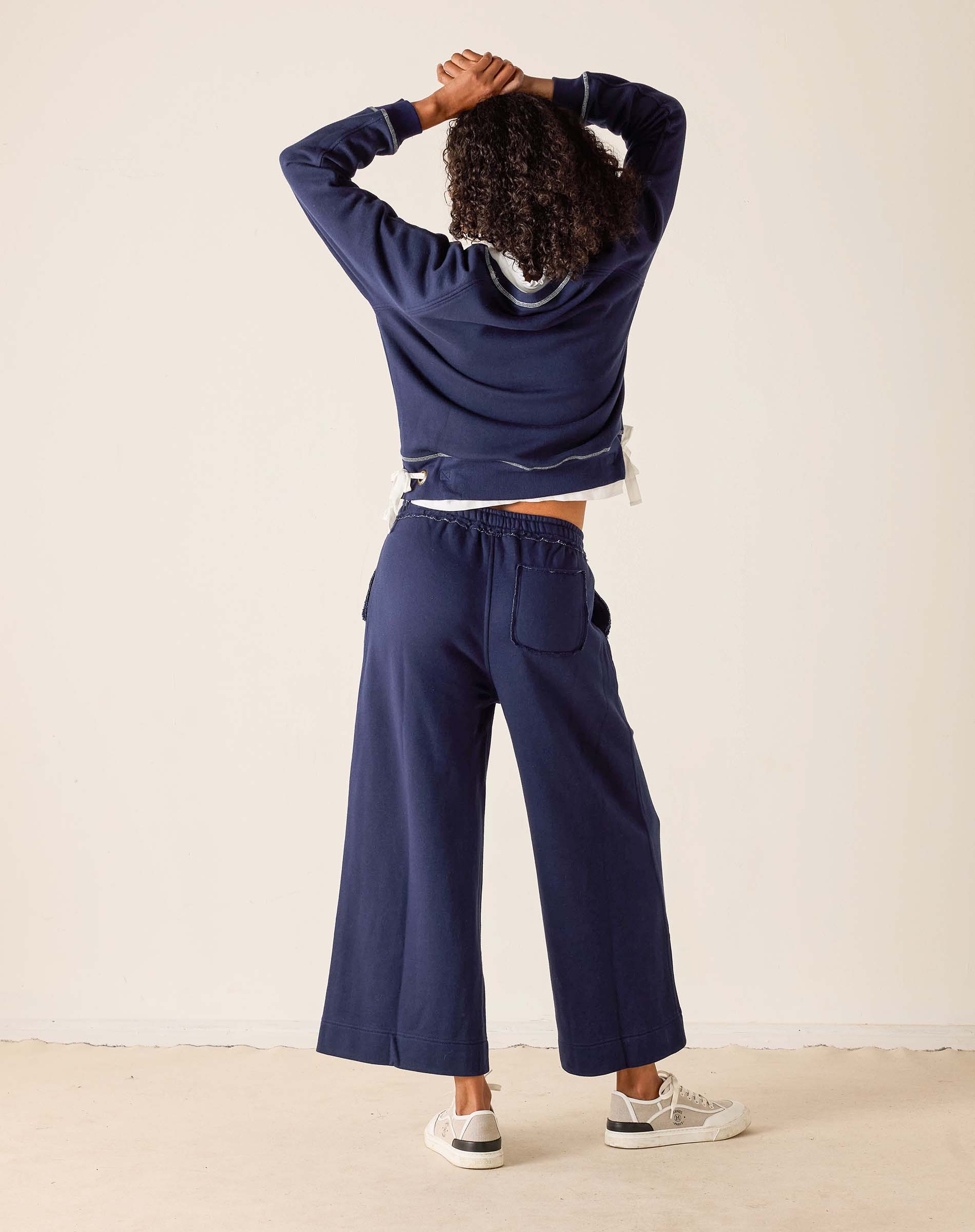 Person wearing a navy blue tracksuit against a white background