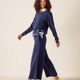 Woman wearing a navy blue outfit with white sneakers on a plain background