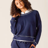 Woman wearing a navy blue outfit with white trim on a beige background