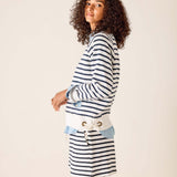 Woman wearing a striped sweater and denim skirt on a plain background