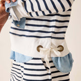 Nautical-style jacket with blue and white stripes and button details on a neutral background