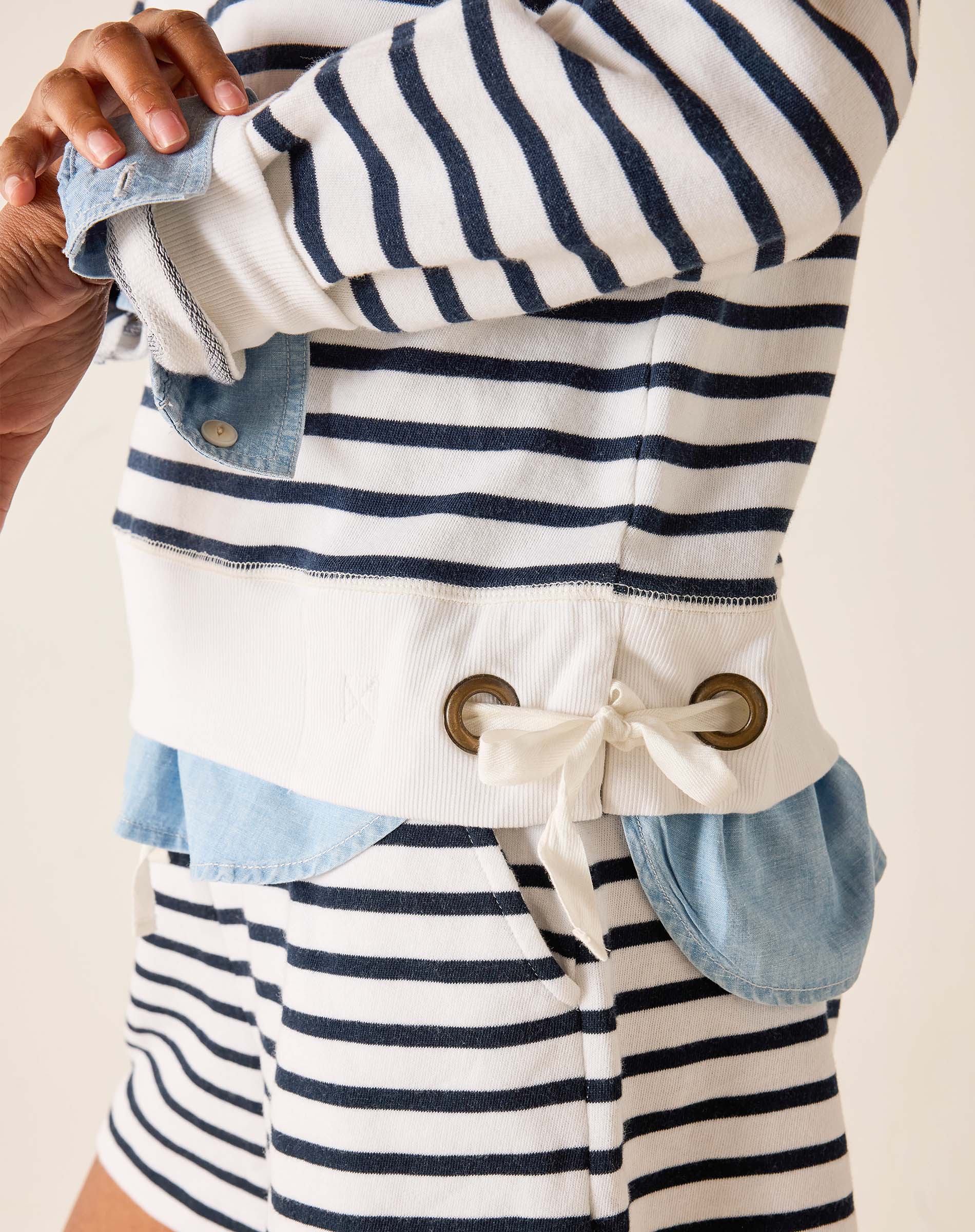 Nautical-style jacket with blue and white stripes and button details on a neutral background
