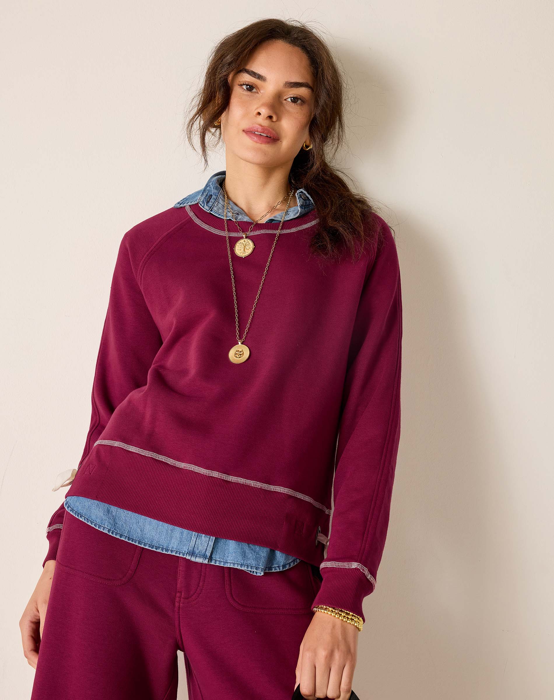 Woman wearing a burgundy sweater with denim collar against a beige background