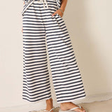 Person wearing black and white striped pants with a plain background