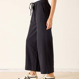 Person wearing black wide-leg pants with a white background