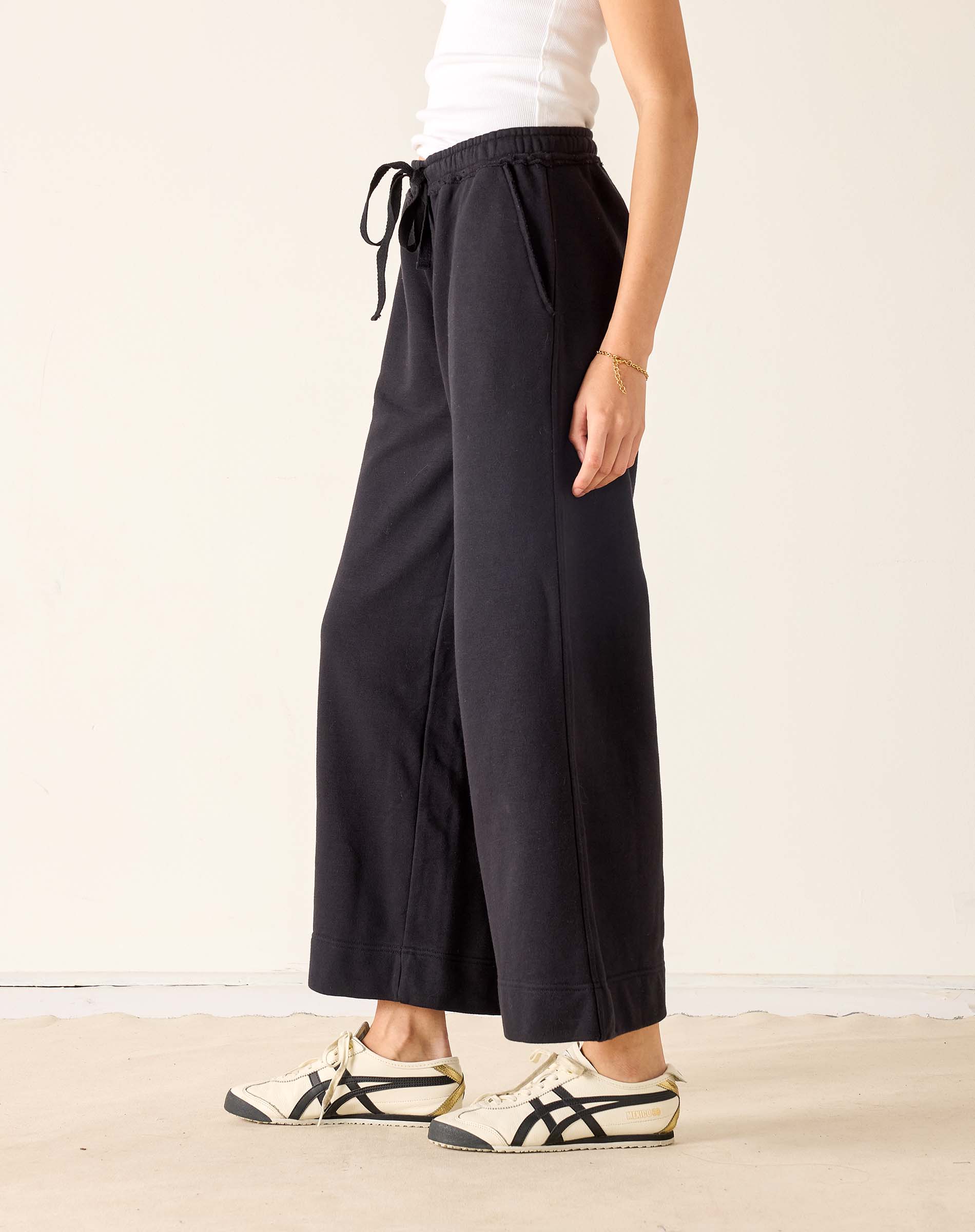 Person wearing black wide-leg pants with a white background