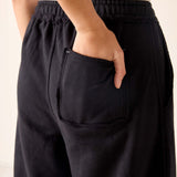 Person wearing black pants with a pocket, on a plain background