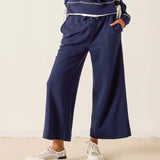 Person wearing navy blue pants and a matching top on a beige background