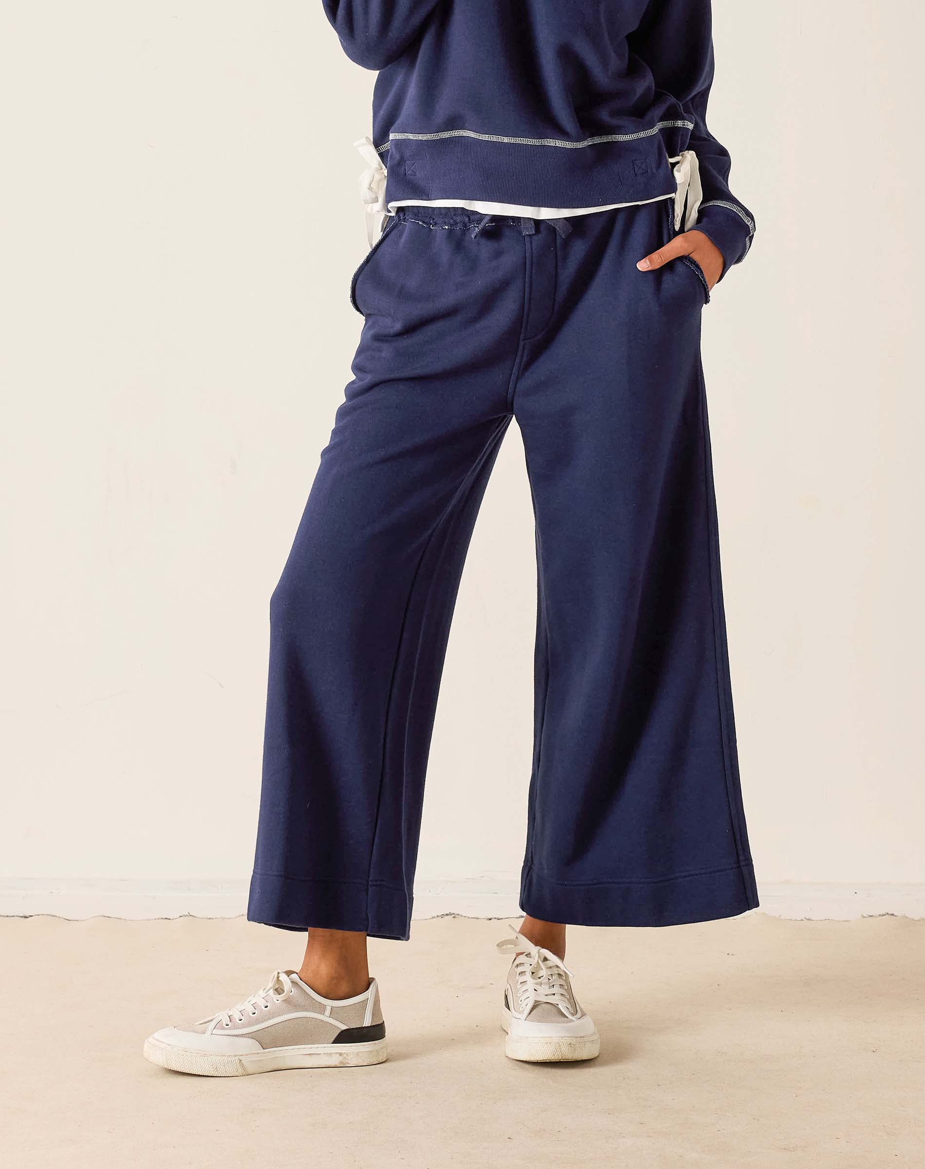 Person wearing navy blue pants and a matching top on a beige background