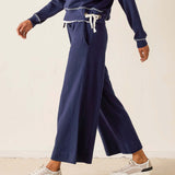Person wearing navy blue sweatpants and a matching top on a beige background