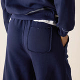 Navy blue sweatpants with a front pocket on a beige background