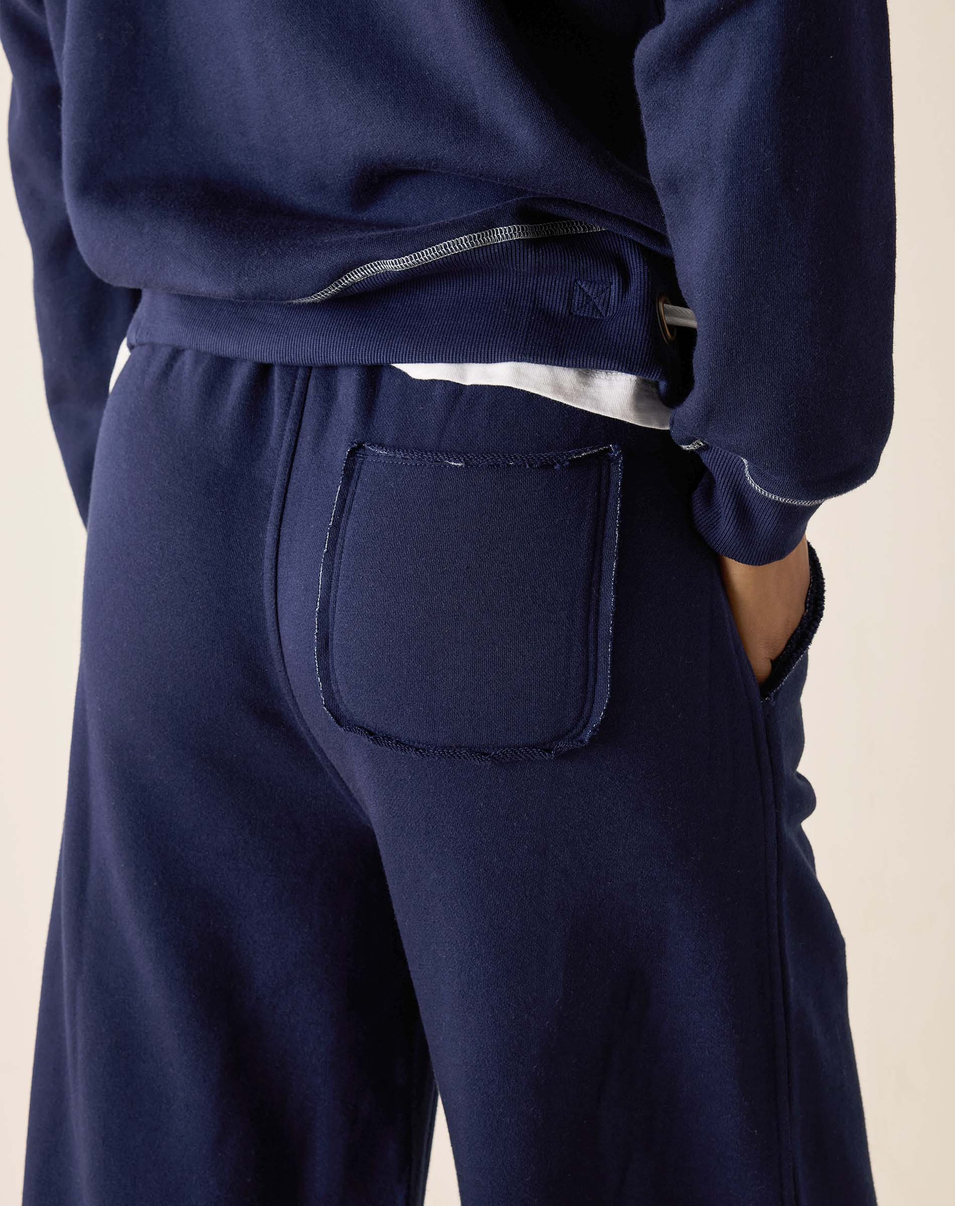 Navy blue sweatpants with a front pocket on a beige background