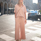 Woman in a pink outfit standing on a city street