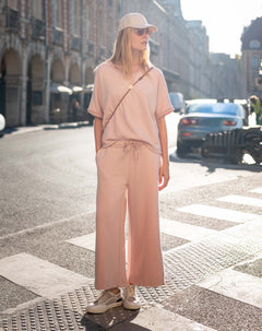 Woman in a pink outfit standing on a city street