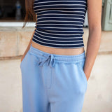 Person wearing a navy and white striped tank top and light blue sweatpants.