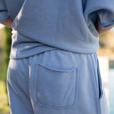 Light blue sweatshirt and pants with a pocket, blurred natural background