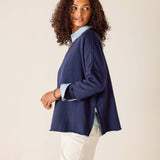 Woman wearing a navy blazer over a light blue shirt with a beige background