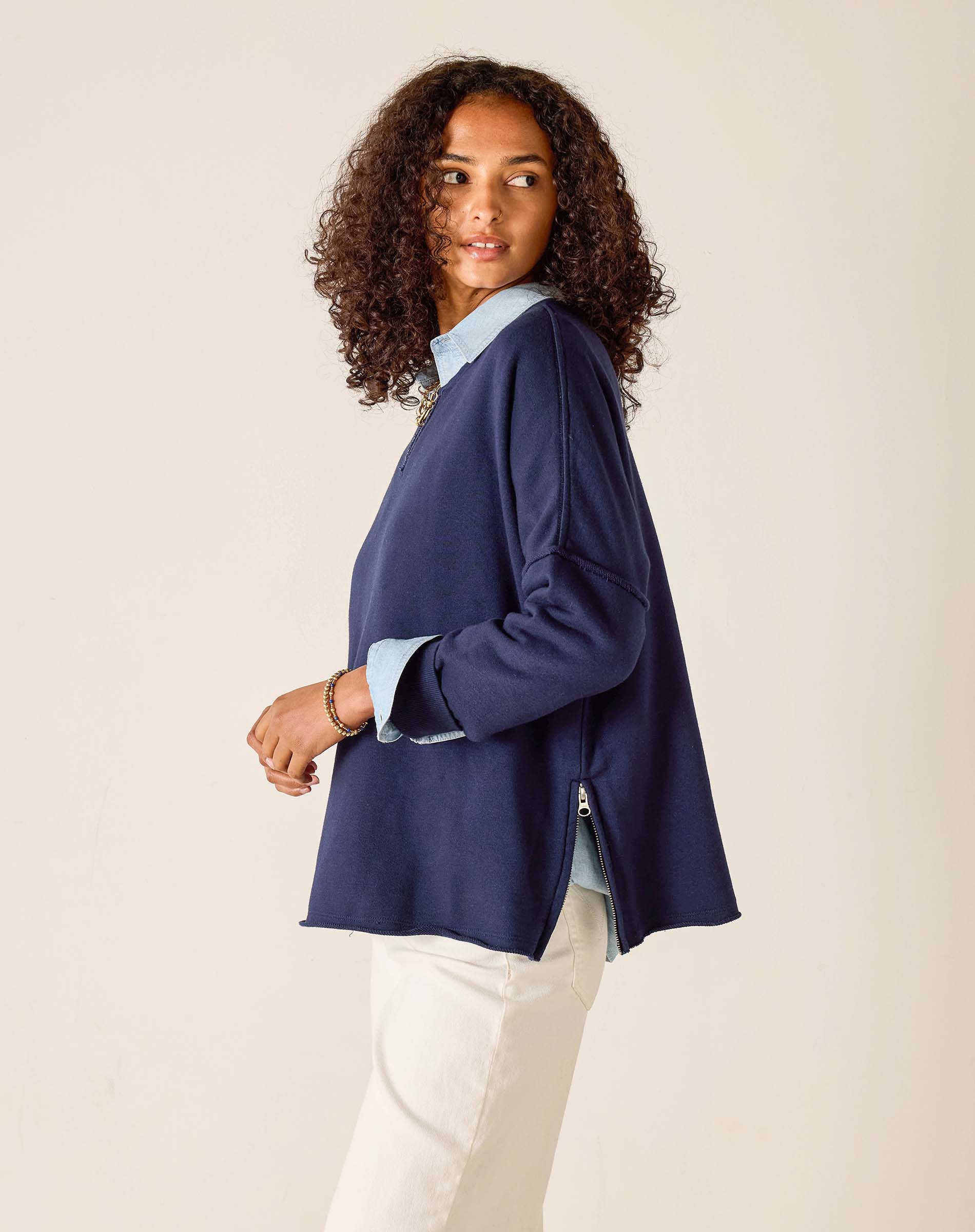 Woman wearing a navy blazer over a light blue shirt with a beige background