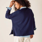 Person wearing a navy blue jacket over a light blue shirt with a beige background