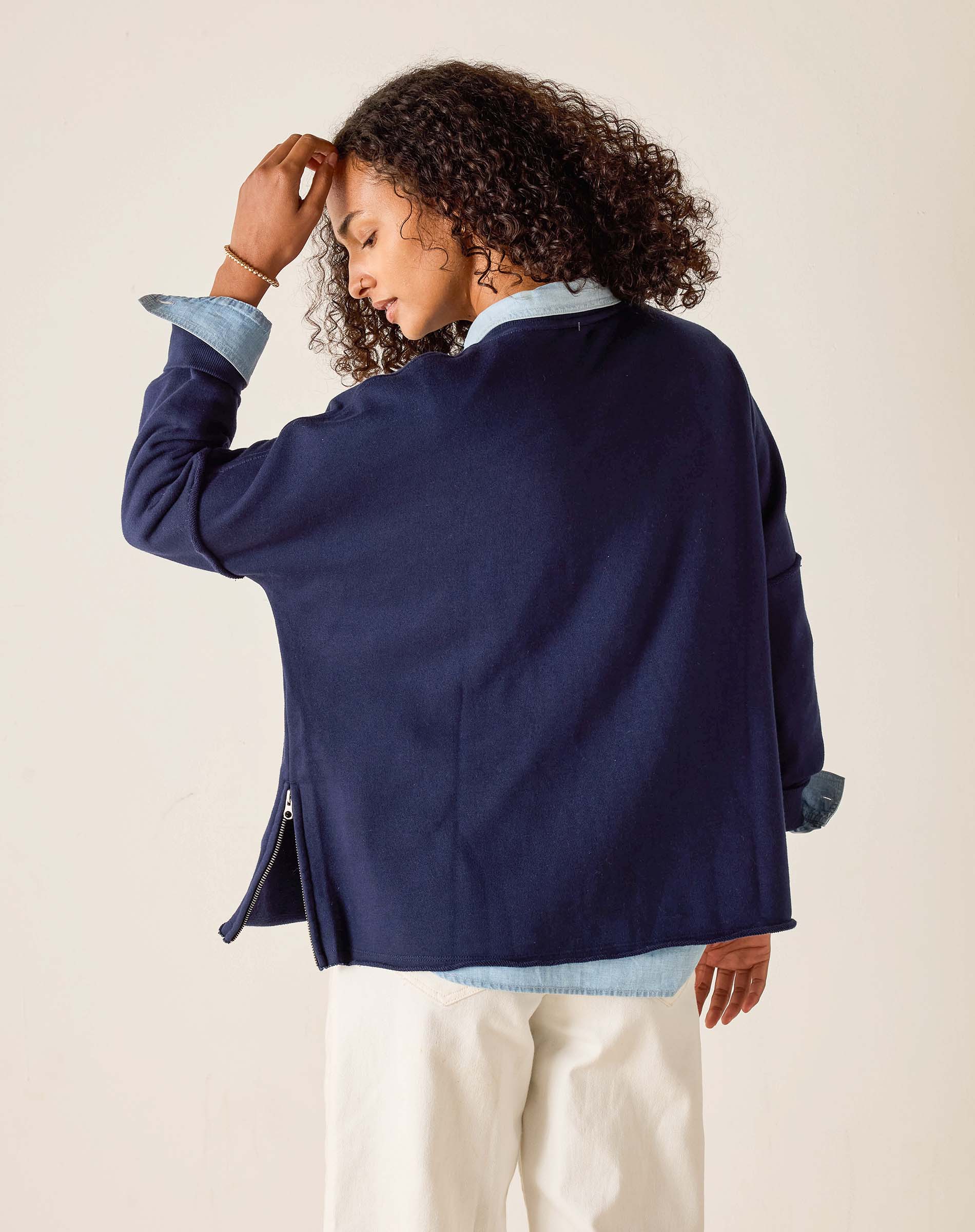 Person wearing a navy blue jacket over a light blue shirt with a beige background
