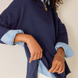 Person wearing a navy blue jacket with denim sleeves and cuffs, on a plain background.