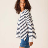 Woman wearing a striped sweater and denim shorts on a plain background