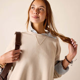 Bone-colored crewneck knit top with a triangular neck detail and a layered button-up shirt.