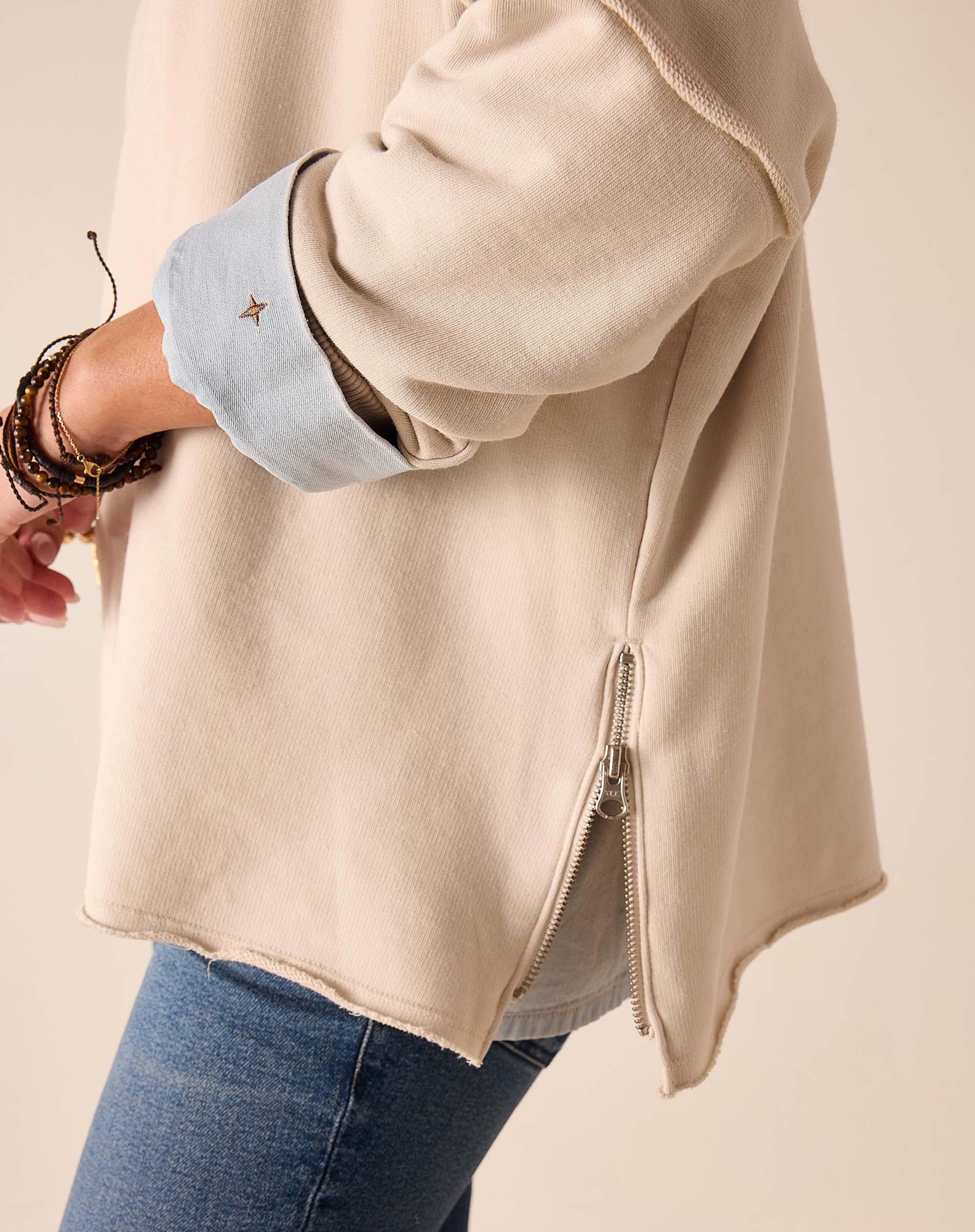 Bone-colored crewneck knit top with long sleeves and a zipper detail.