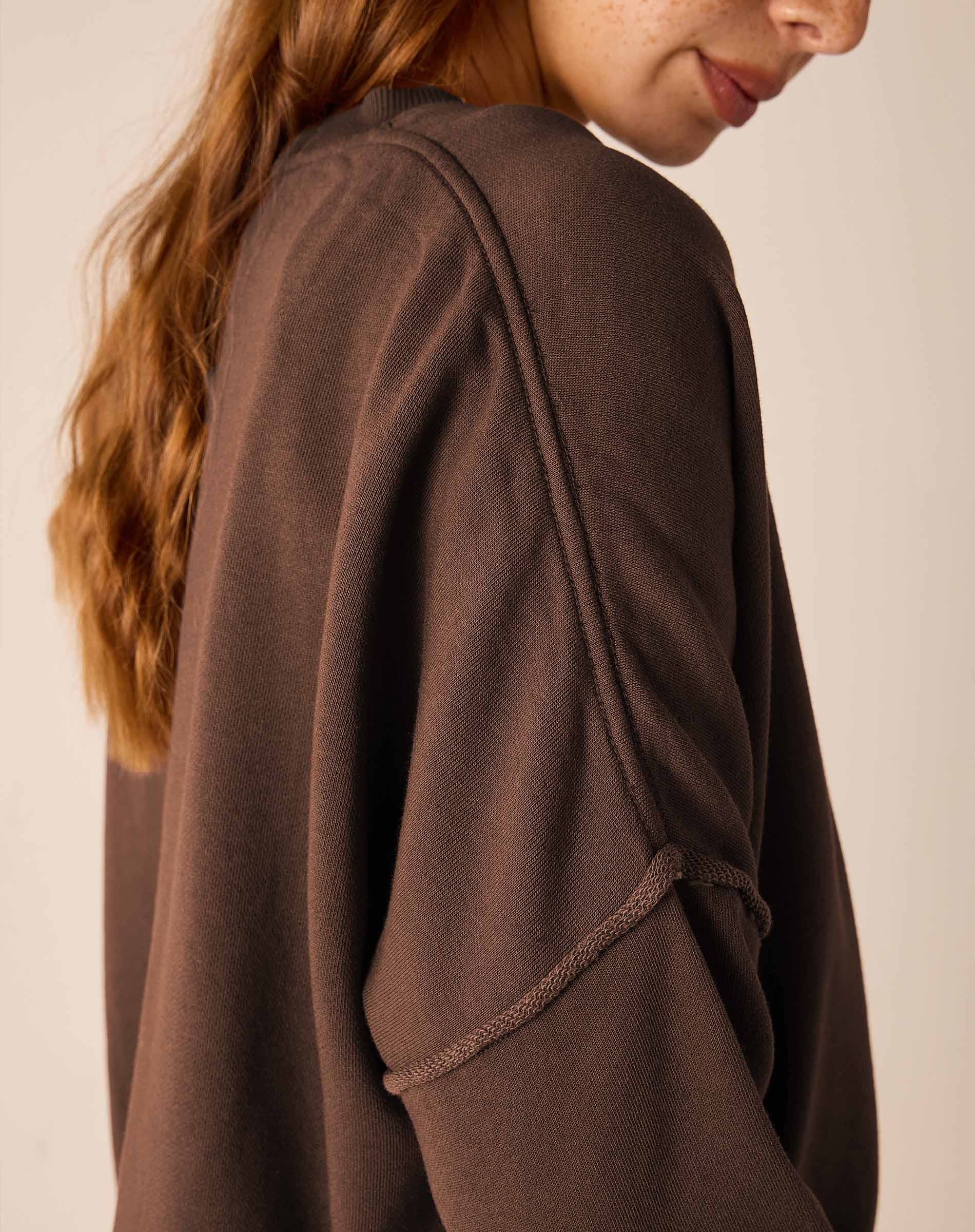 Side view of the espresso knit crewneck top with a decorative zipper detail.
