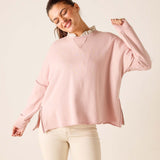Woman wearing a pink sweater with a white collar against a beige background