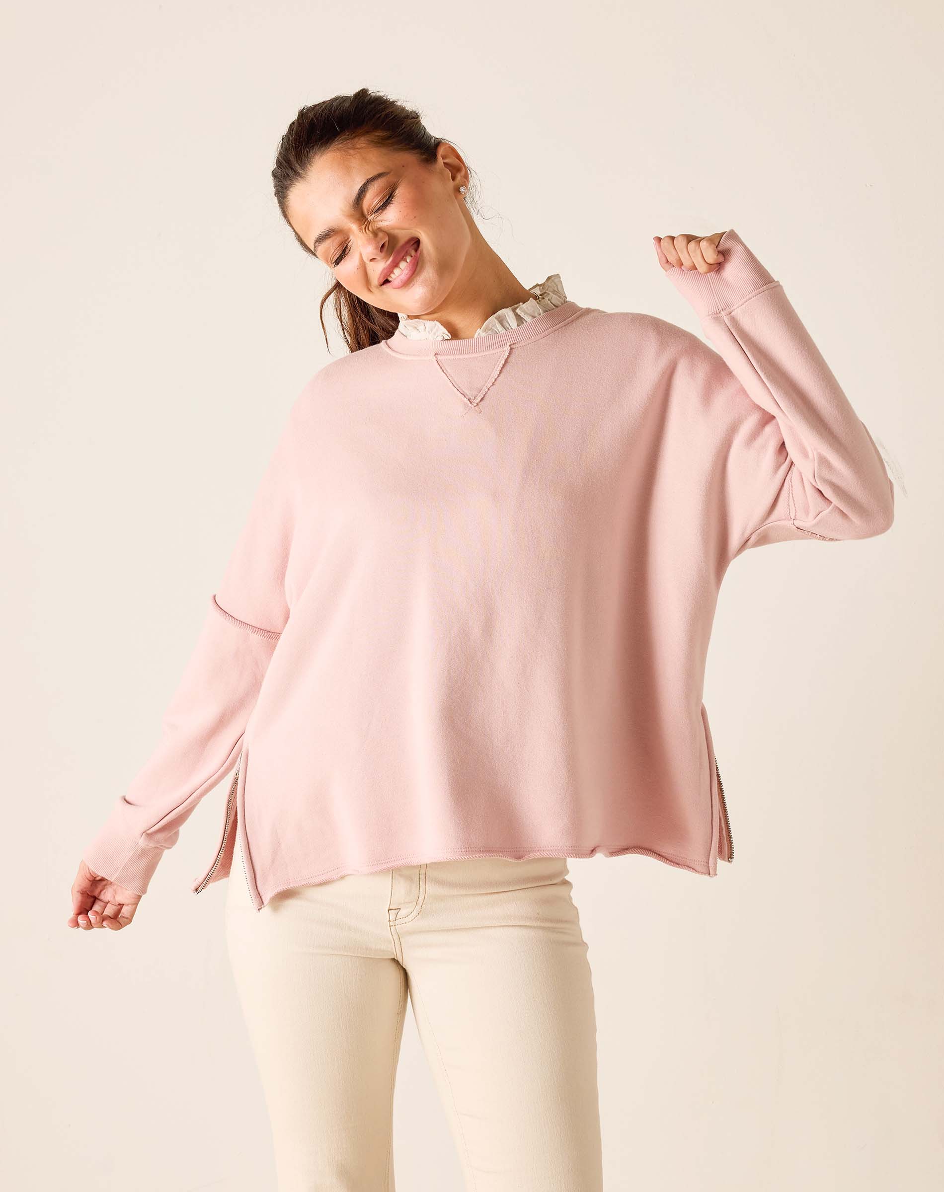Woman wearing a pink sweater with a white collar against a beige background