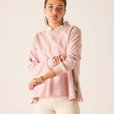 Woman wearing a pink sweater with a white collar against a beige background
