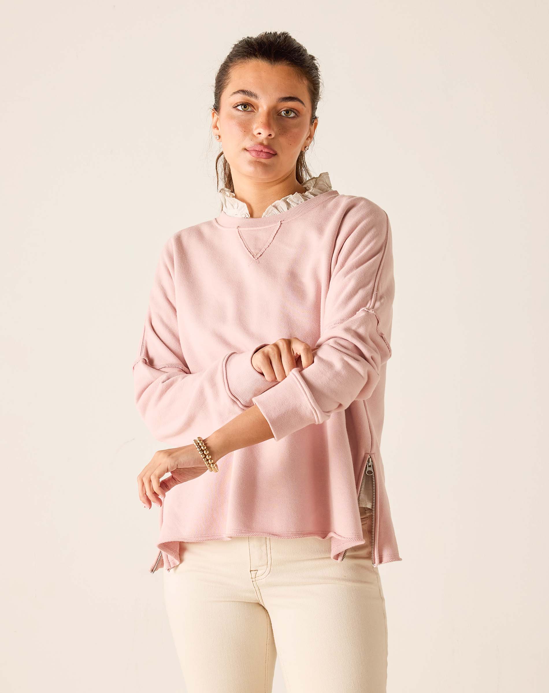 Woman wearing a pink sweater with a white collar against a beige background