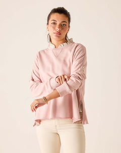 Woman wearing a pink sweater with a white collar against a beige background